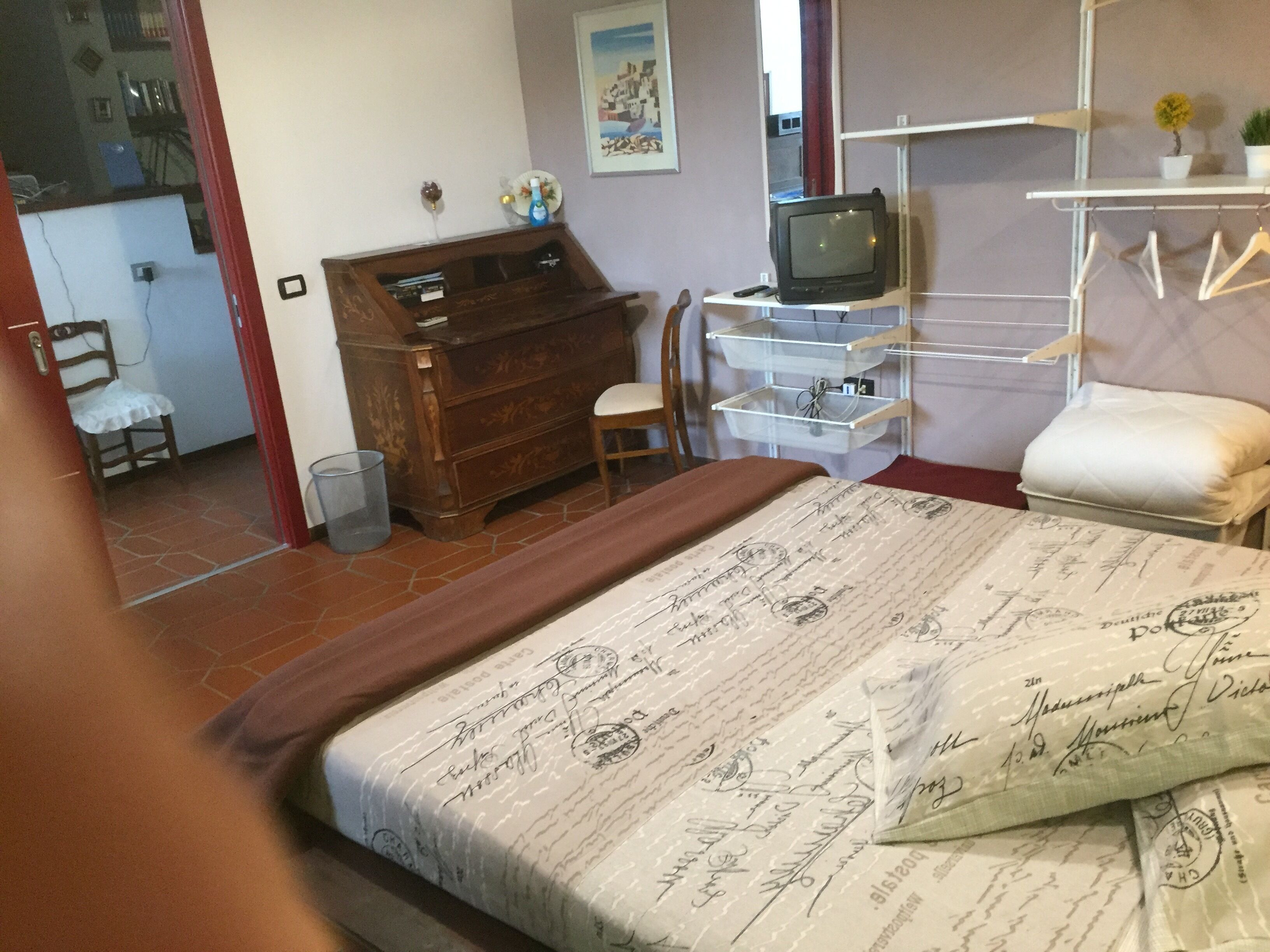 Une chambre à coucher avec un lit, une commode en bois, un téléviseur et une petite table avec une chaise.