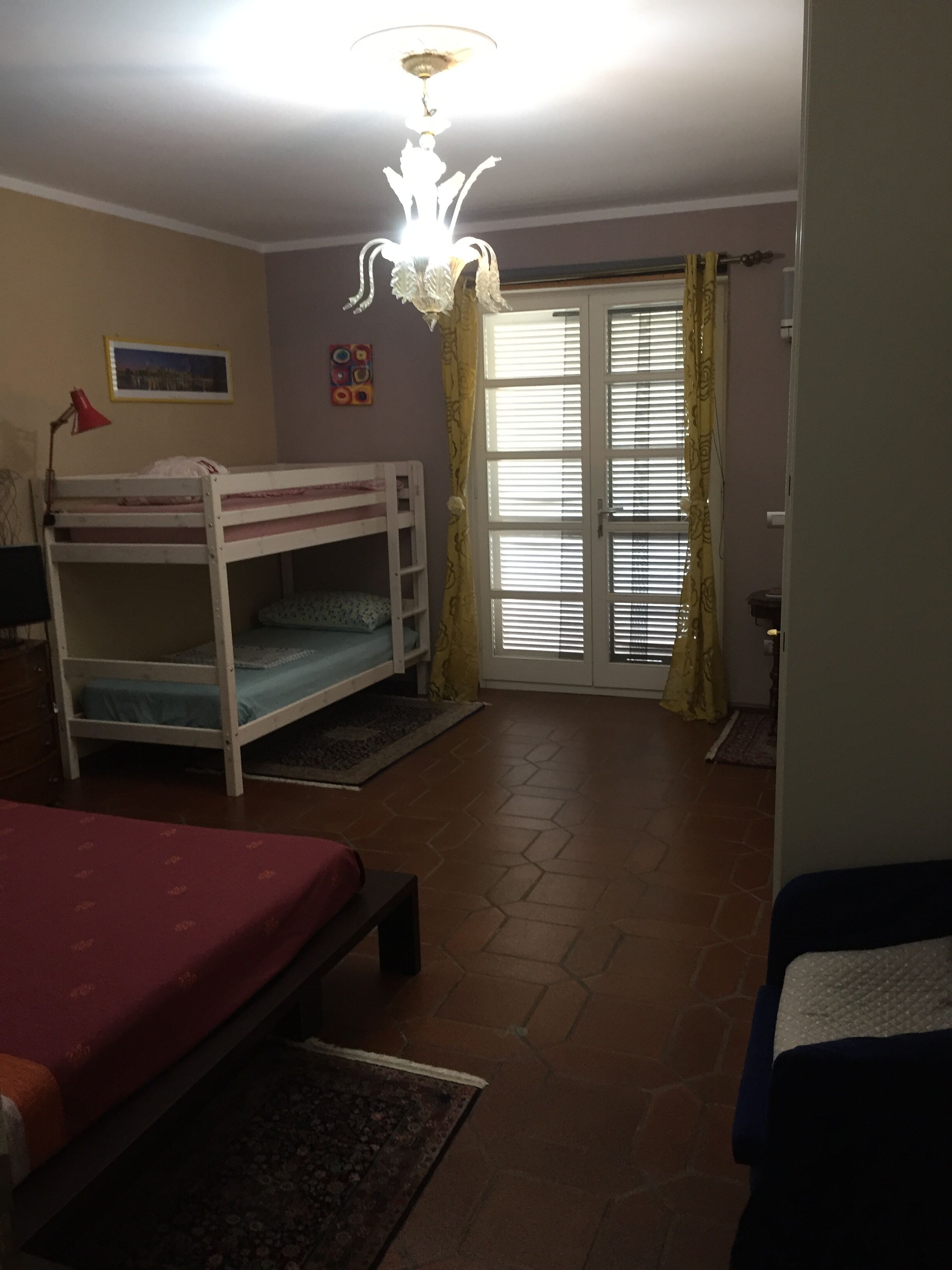 Ein Zimmer mit Etagenbett, Schreibtisch, Stuhl und einem Fenster mit Vorhängen.