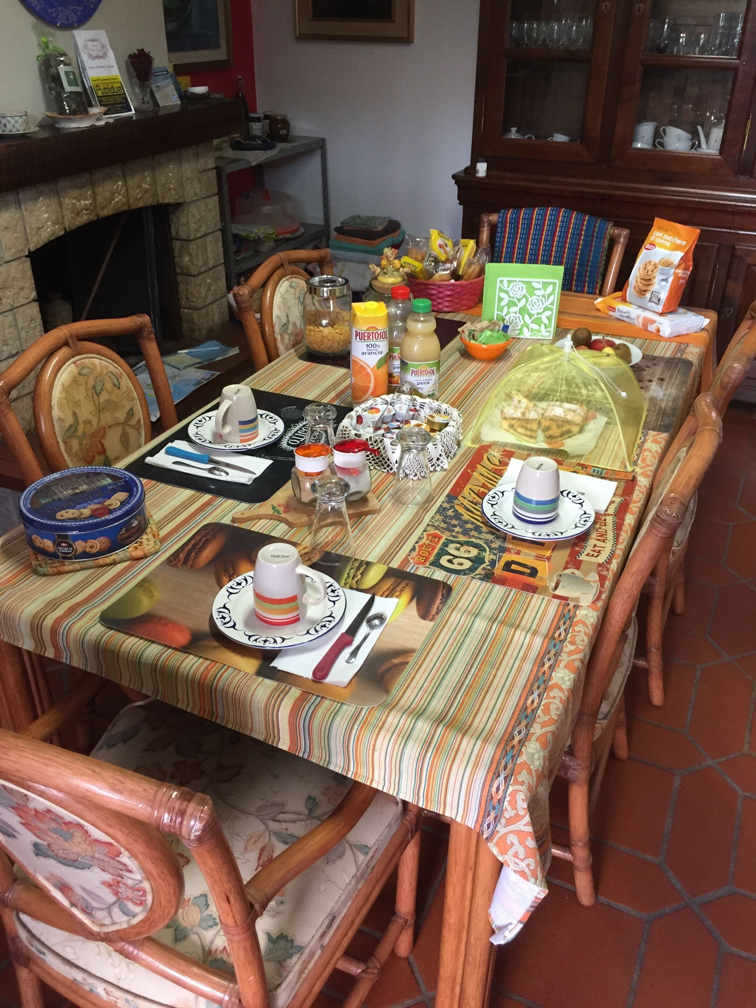A dining table set with plates, cutlery, and various food items, surrounded by wooden chairs.