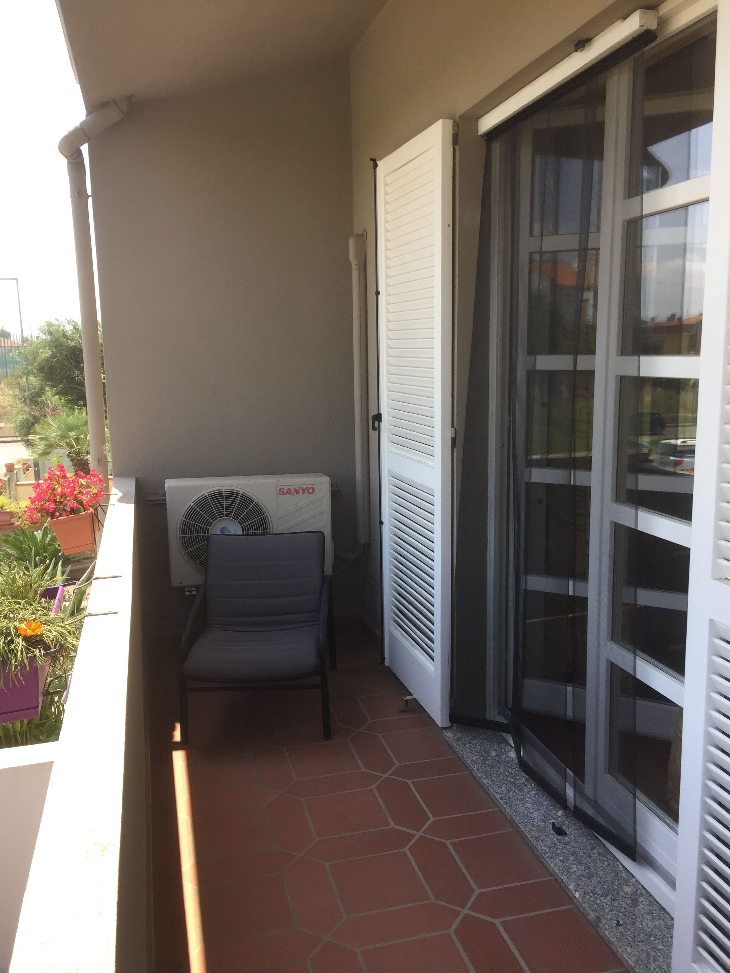 A balcony with a chair, a window with blinds, and a radiator.