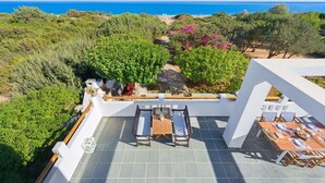 A terrace with a table and chairs, overlooking a coastal landscape with trees and a view of the sea. - Beachfront Villa Akti (Gennadi area)
