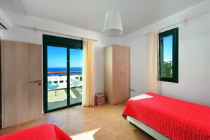 A bedroom with a bed, a wardrobe, a window, and a view of the sea. - Beachfront Villa Akti (Gennadi area)