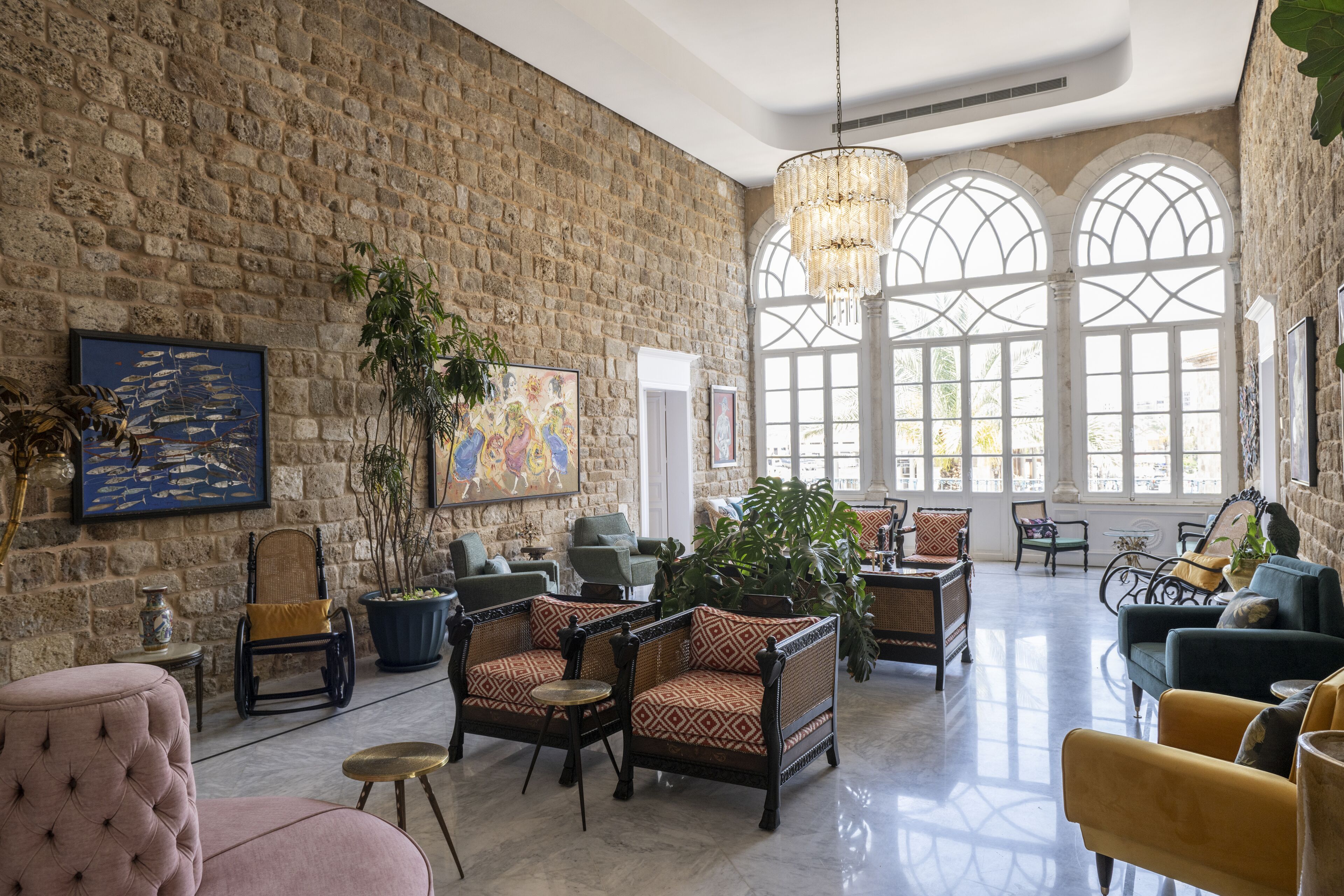 A spacious lobby with stone walls, large windows, and various seating arrangements including armchairs and sofas.