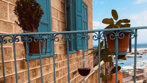 A balcony with a wooden table and a chair, a potted plant, and a view of boats and a beach. - Dar Alice (Tyre)