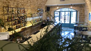 A bar area with shelves of liquor bottles, a counter, and seating. - Dar Alice (Tyre)