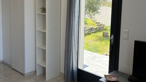 Een moderne kamer met een schuifglasdeur naar een balkon, een witte kast en een klein tv-meubel.