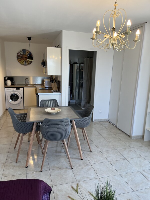 A modern kitchen with a built-in washing machine, a dining area with a table and chairs, and a chandelier.