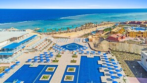 Een resort met een groot zwembad, ligbedden en een strand.