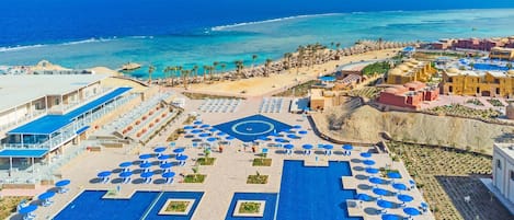 A resort with a large pool area, sun loungers, and a beach.