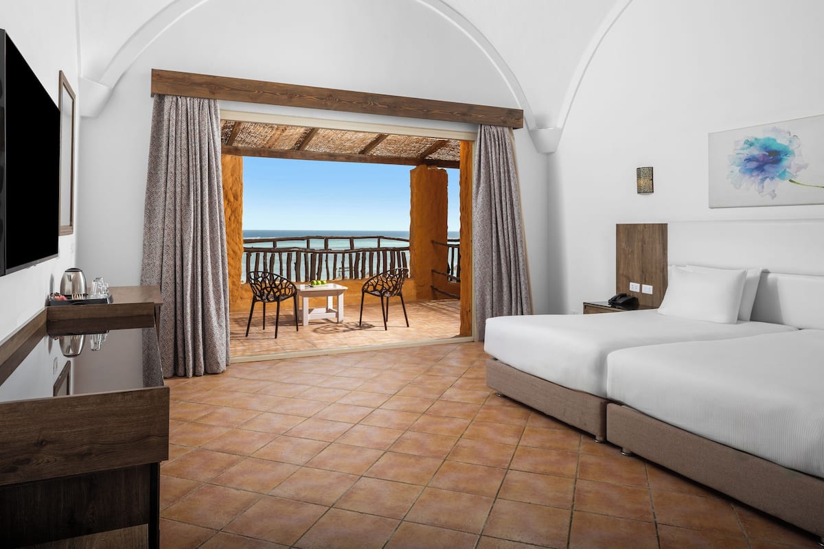 Een hotelkamer met balkon, bed, bureau en televisie.