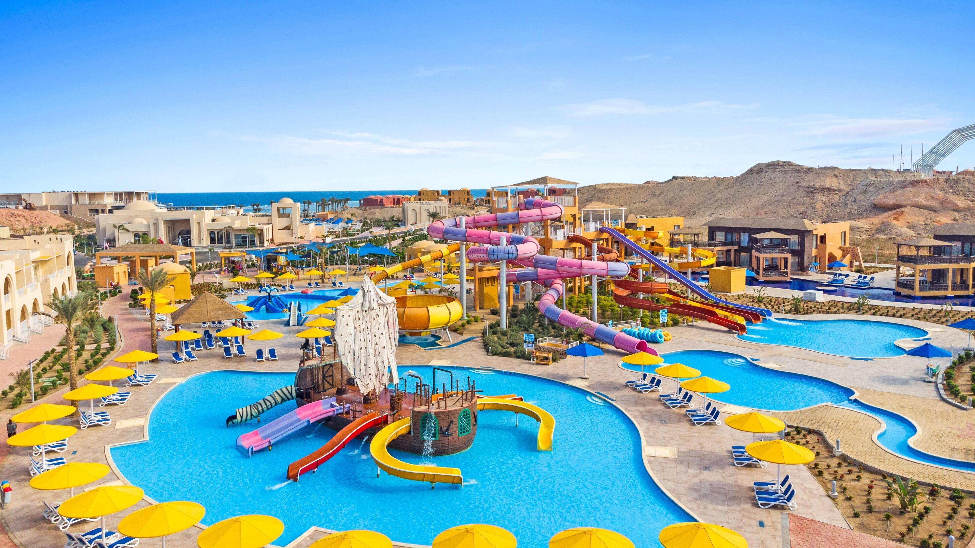 Ein Resort mit mehreren Schwimmbecken, Wasserrutschen und Liegestühlen.