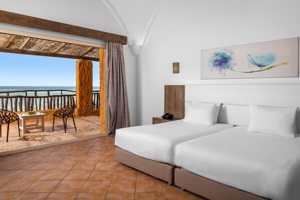 Une chambre d’hôtel avec un balcon, un lit, une table, deux chaises et un tableau au mur.