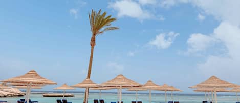 En la playa, sombrillas, toallas de playa y vóleibol de playa