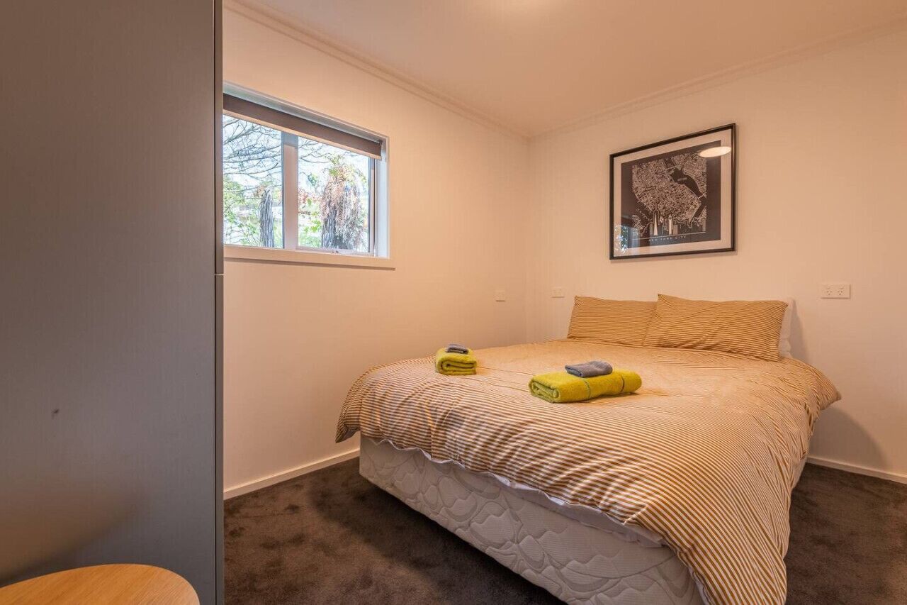 Un dormitorio con cama, ventana y un cuadro en la pared.