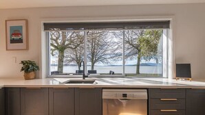 Una cocina moderna con un ventanal grande, lavavajillas y una planta en maceta.