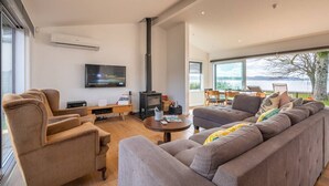 Amplia sala de estar con un sofá grande, televisor, chimenea y vistas al exterior.