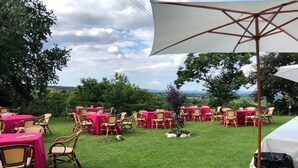 An outdoor dining area with tables and chairs, a white umbrella, and a view of the landscape. - 150 sq. m. apartment in villa with private pool and Jacuzzi (Fabrica di Roma)