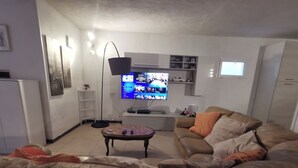 A living room with a large flat-screen TV, a sofa, a coffee table, and a floor lamp. - 150 sq. m. apartment in villa with private pool and Jacuzzi (Fabrica di Roma)