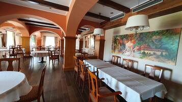Un ristorante con tavoli comuni lunghi, sedie di legno e un grande murale sulla parete.