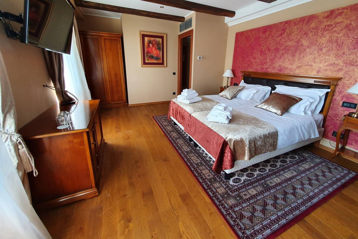 Ein Hotelzimmer mit einem hölzernen Bett, einem roten Teppich mit Muster und einem Holzschrank.