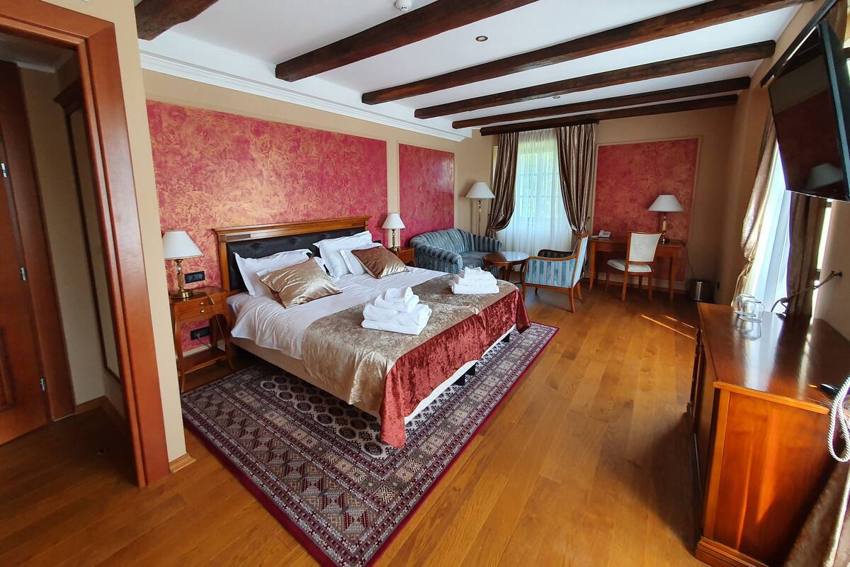 Ein Hotelzimmer mit einem großen Bett, einem Schreibtisch, einem Sessel und einem Fernseher.
