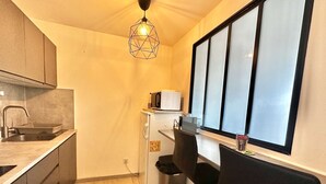 A compact kitchen with a sink, countertop, and a window with blinds. - Capucine, Duplex à 5 min de la mer (Courseulles-sur-Mer)