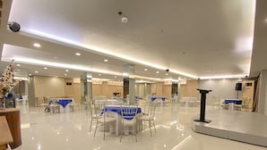 A spacious, well-lit banquet hall with multiple tables and chairs, a podium, and a stage area. - Hotel Estrella (Tacloban)