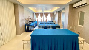 A conference room with a long table, white chairs, and a blue tablecloth. - Hotel Estrella (Tacloban)