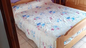 Makuuhuone, jossa on puinen sänky, violetit seinät ja puinen vaatekaappi.