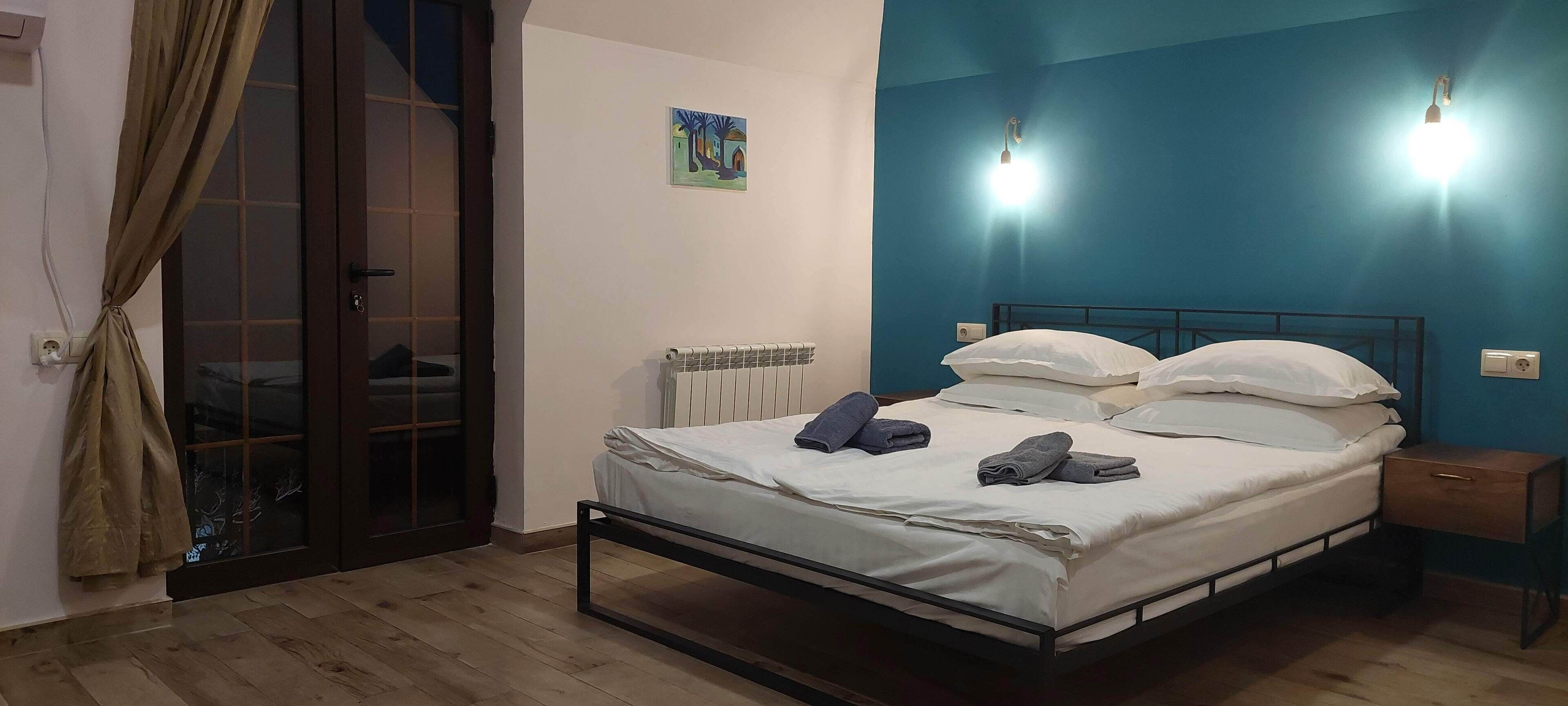 Ein Schlafzimmer mit Bett, Heizkörper, Nachttisch und einem Fenster mit Vorhängen.