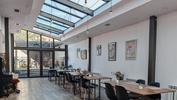 A modern dining area with a high ceiling, skylights, and a view of the outdoors. - Blur Inn Gallery Hotel (Yerevan)
