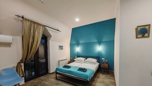 A bedroom with a bed, a chair, a nightstand, and a blue accent wall. - Blur Inn Gallery Hotel (Yerevan)