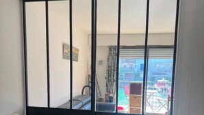 Un balcone con vista su una zona residenziale, un divano con cuscini decorati e una finestra che affaccia su un balcone esterno.