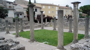 Ancient ruins with stone columns, a grassy area, and buildings in the background. - Gîte de la Méouge (Barret-sur-Méouge)
