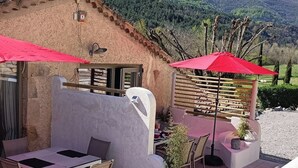Un patio con mobiliario exterior, un muro de piedra y vistas a la montaña.
