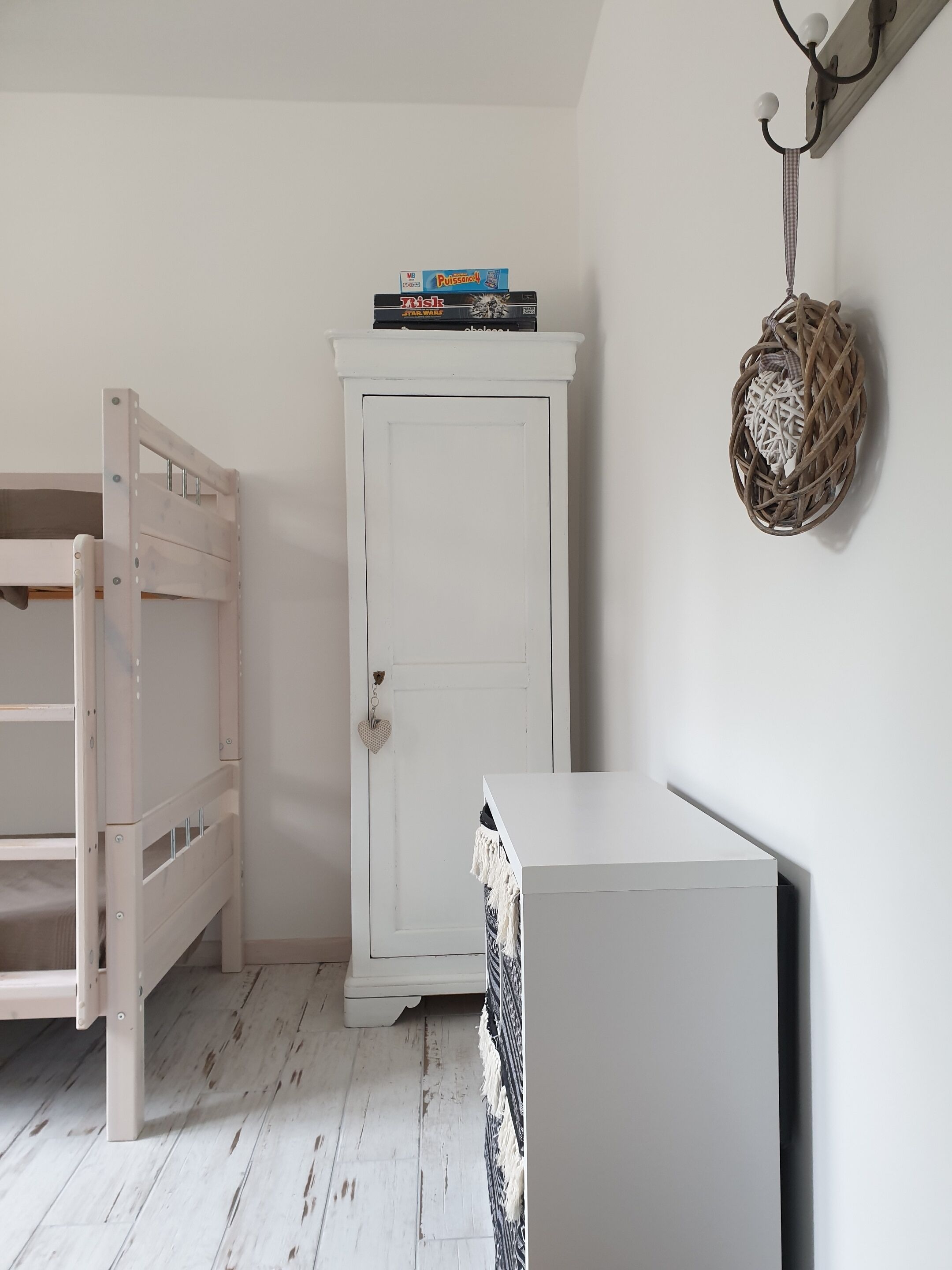 Une pièce avec une armoire blanche, un meuble blanc et un lit en bois.