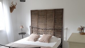 Un dormitorio con cama, mesita de noche, lámpara, cabeza de venado decorativa y lámpara colgante.
