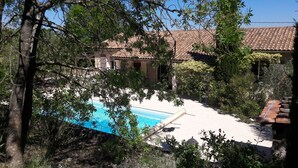 Una piscina rodeada de árboles y un edificio con techo de tejas.