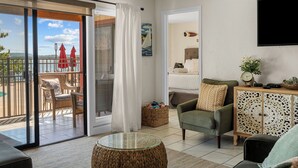 A living room with a glass door leading to a balcony, a sofa, a chair, a small table, and a cabinet with decorative panels. - Table Rock Lake Views | Pool Steps from Patio | 2 Private Suites (Kimberling City)