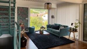 A modern living room with a staircase, a sofa, a coffee table, and a view of the outdoors. - Exceptional mountain view, heated swimming pool, 10 minutes from Lake Annecy (sillingy)