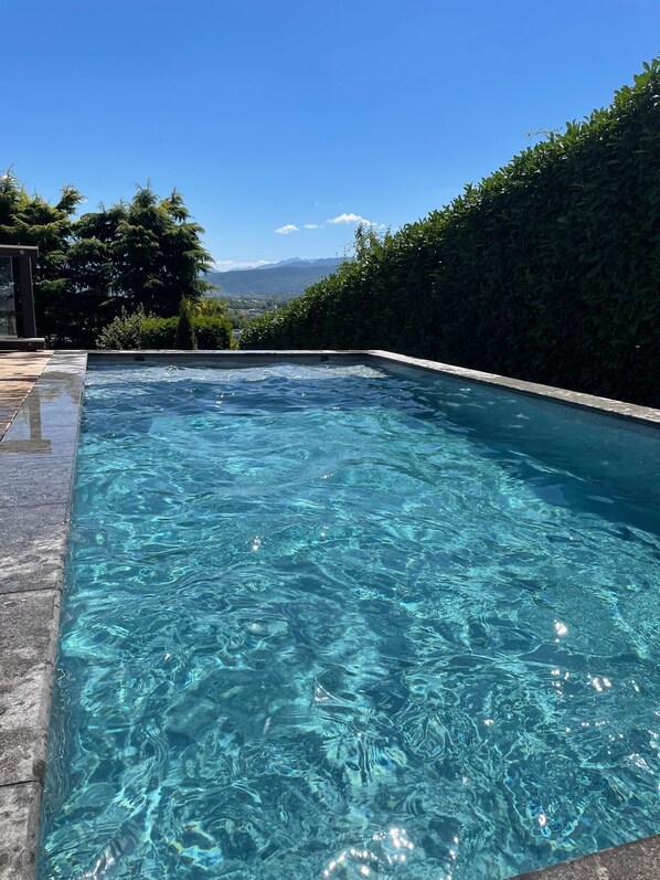 A clear swimming pool with a view of mountains in the background.