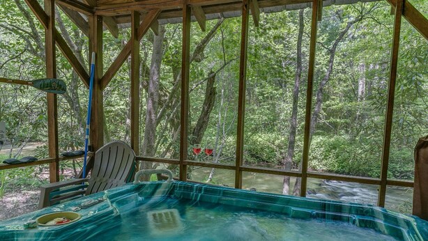Un bain à remous dans un gazebo en bois, avec vue sur une forêt.