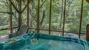 A hot tub in a wooden gazebo with a view of a forest.