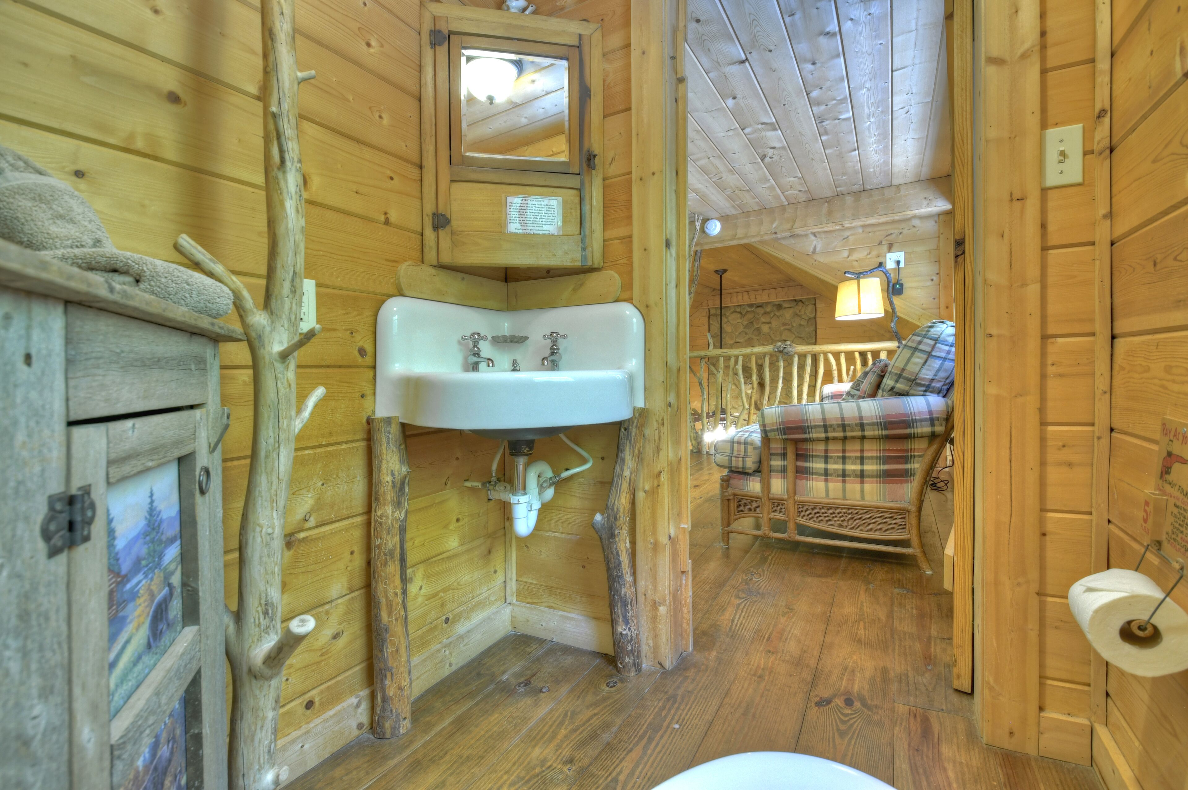 L’intérieur d’un chalet rustique en bois, avec un banc en bois, un évier blanc et un miroir au-dessus.