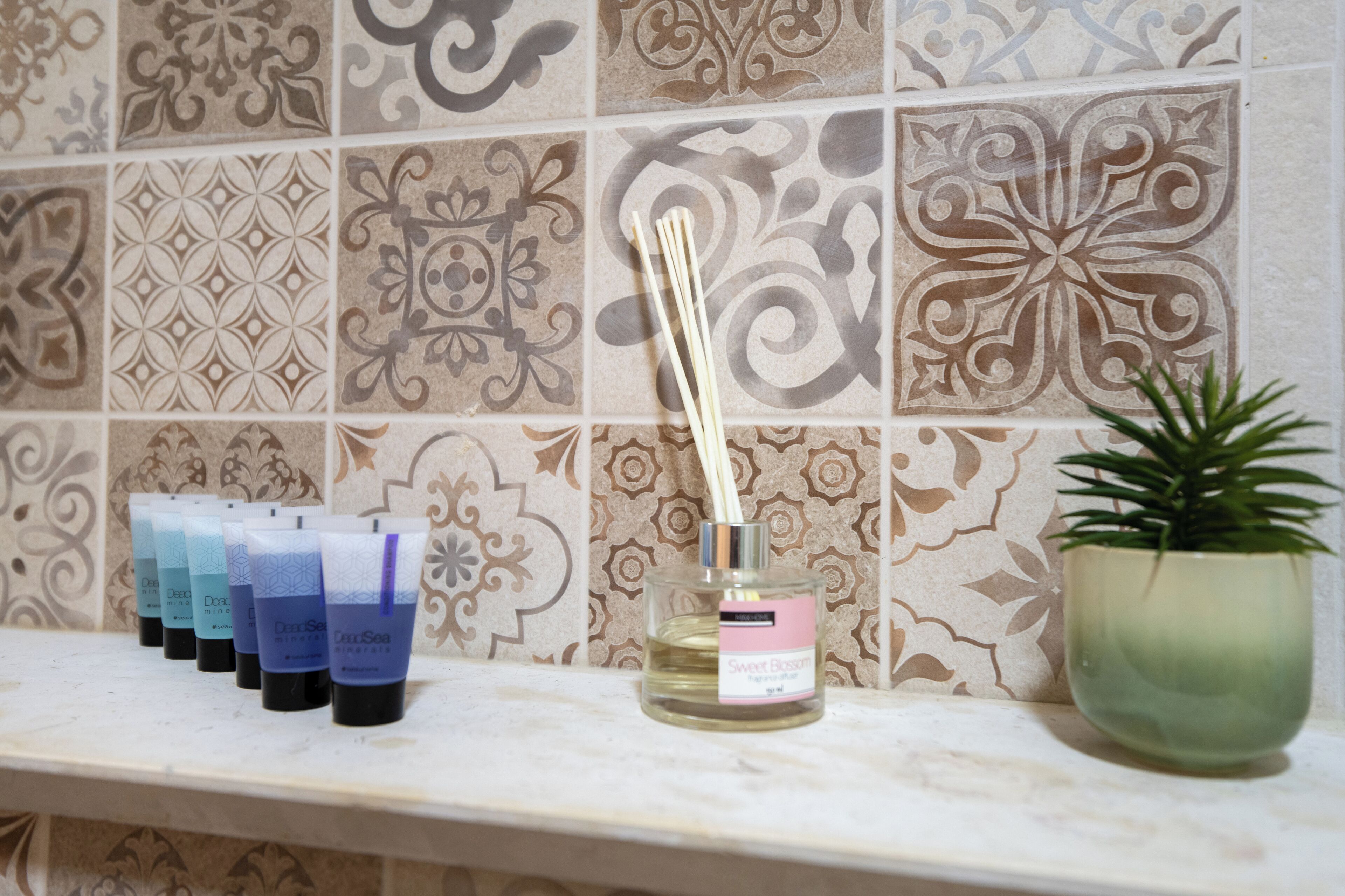 A shelf with various scented candles and a diffuser bottle.