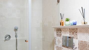 A bathroom with a glass shower enclosure, a toilet, and a sink.