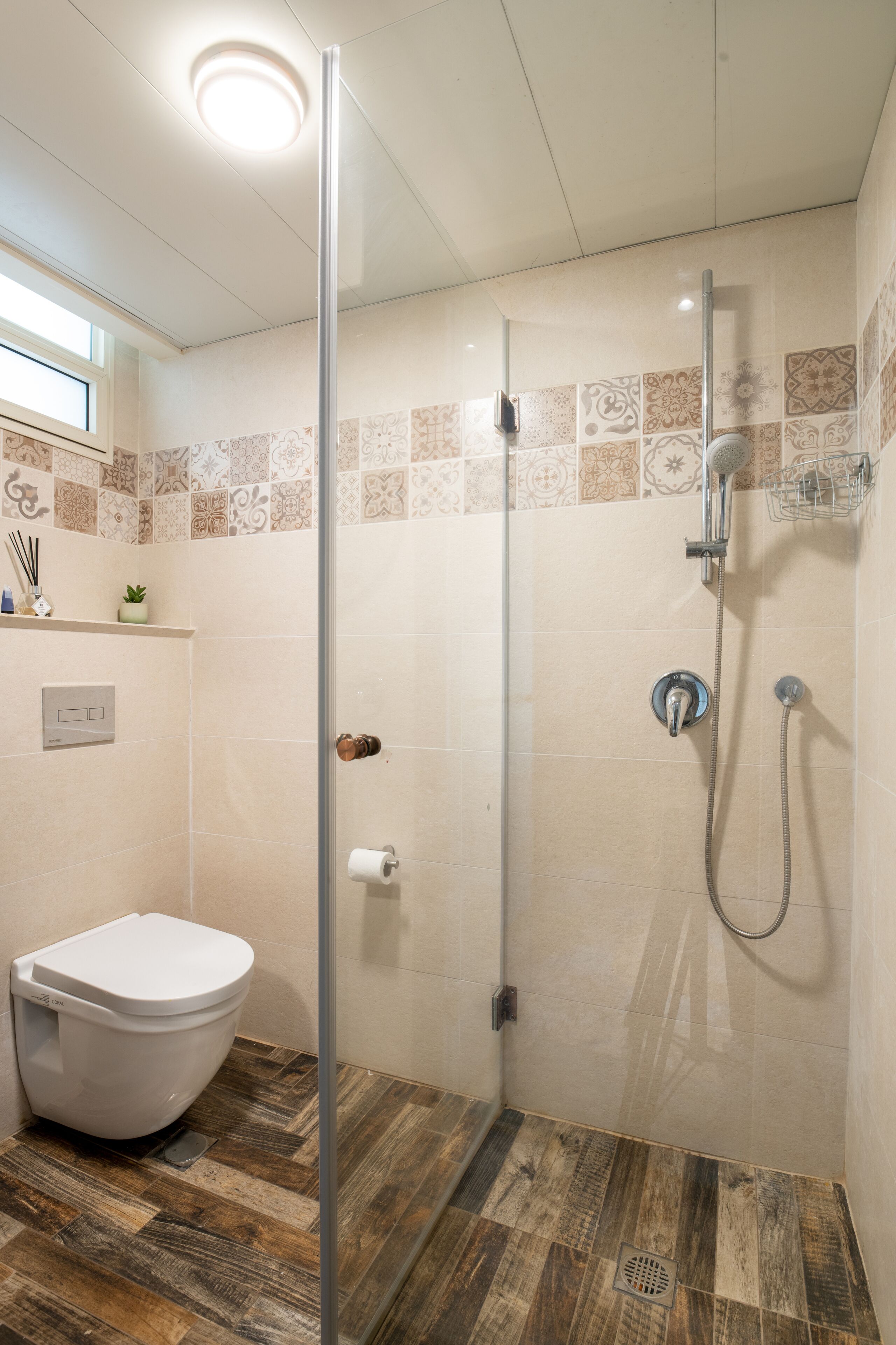 A bathroom with a shower, toilet, and a tiled backsplash.
