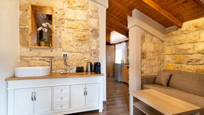 A bathroom with a stone wall, wooden ceiling, and a white sink with cabinets. - Via Maria Boutique Suites (Haifa)