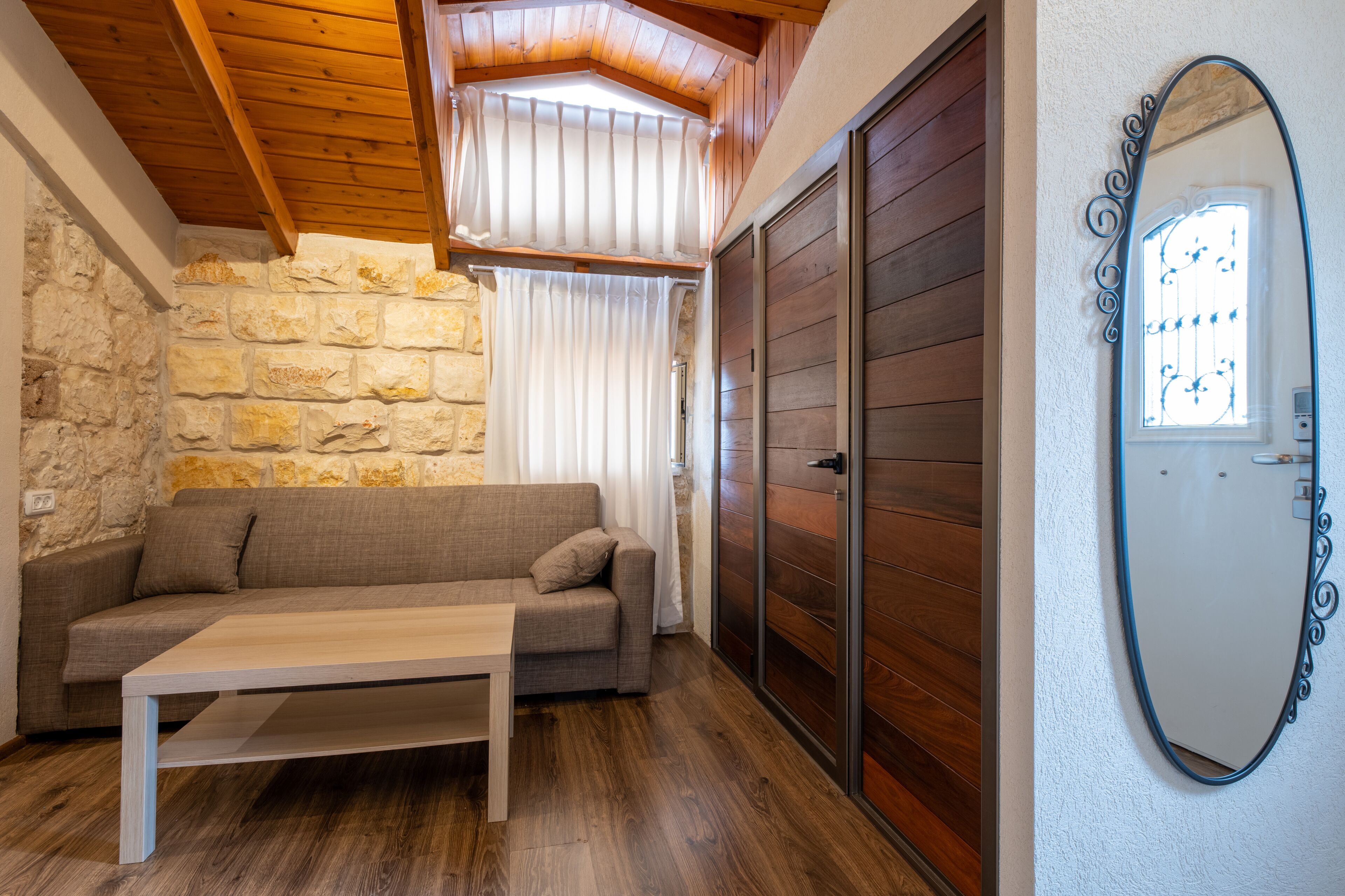 Una habitación acogedora con pared de piedra, techo de madera, un sofá, una mesa y una puerta corredera.