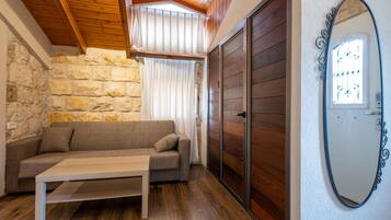 Una habitación acogedora con pared de piedra, techo de madera, un sofá, una mesa y una puerta corredera.
